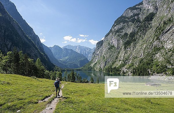 Hiker on the way to the lake Obersee  view over the Obersee  behind the Watzmann  Berchtesgaden National Park  Berchtesgaden Alps  Berchtesgadener Land  Bavaria  Germany  Europe