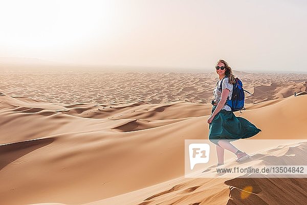 Wanderin auf einer roten Sanddüne in der Wüste  Dünenlandschaft Erg Chebbi  Merzouga  Sahara  Marokko  Afrika