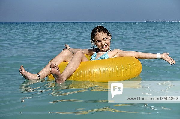 Child sitting happily in a floating tire in the sea  Saadiyat Beach  Abu Dhabi  United Arab Emirates  Asia
