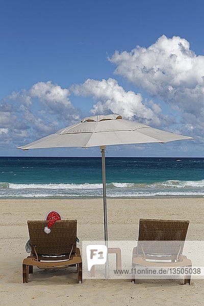 Frau mit Weihnachtsmannmütze im Liegestuhl mit Sonnenschirm am Strand  Playa Bavaro  Punta Cana  Dominikanische Republik  Mittelamerika