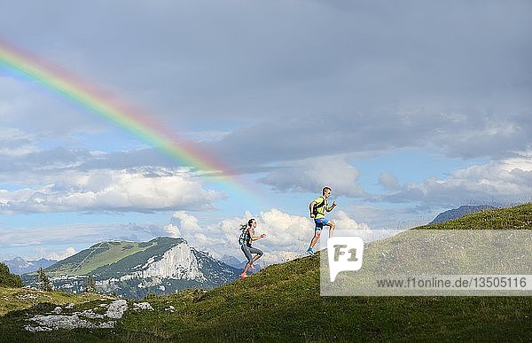 Wanderer  Trailrunning auf der Eggenalm mit Regenbogen  hinter Loferer Steinberge  Reit im Winkl  Oberbayern  Bayern  Deutschland  Europa