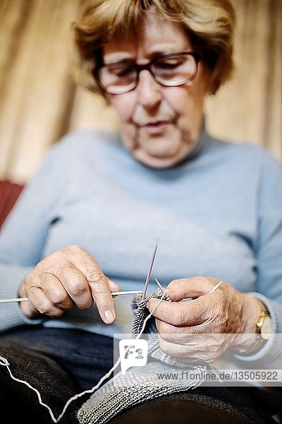 Seniorin strickt zu Hause auf dem Sofa einen Strumpf  Nordrhein-Westfalen  Deutschland  Europa