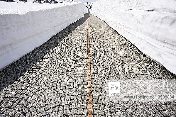 Kopfsteinpflaster der alten Gotthardstraße zwischen hohen Schneewänden  Schweiz  Europa