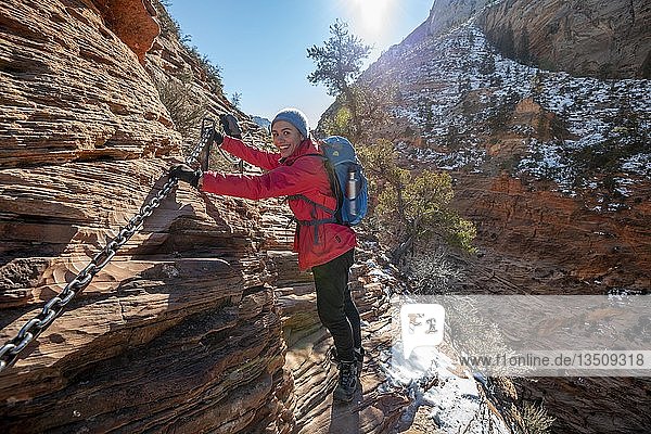 Young woman hiking on the via ferrata of the Angels Landing Trail  in winter  Zion Canyon  mountain landscape  Zion National Park  Utah  USA  North America