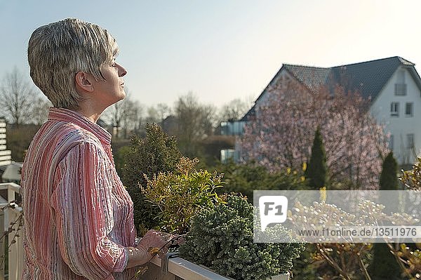 Frau steht auf einem Balkon und genießt die Morgensonne  Grevenbroich  Nordrhein-Westfalen  Deutschland  Europa