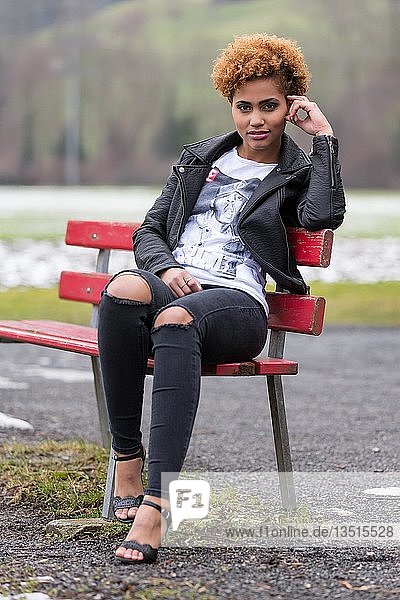 Junge dunkle Frau auf einer Bank sitzend  Mode