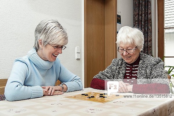 'Two elderly women  senior citizens  mother and daughter  playing the board game ''Nine Men's Morris''  Rehna  Mecklenburg-Western Pomerania  Germany  Europe'