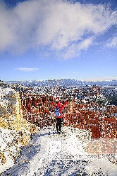Young woman with outstretched arms and a view of the amphitheatre  bizarre snowy rocky landscape with Hoodoos in winter  Rim Trail  Bryce Canyon National Park  Utah  USA  North America