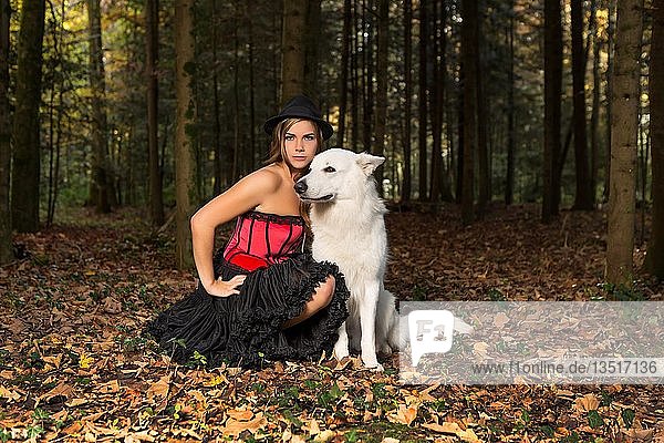 Blonde Frau mit weißem Hirtenhund im Wald