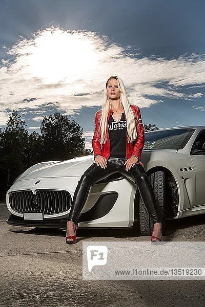 Junge Frau mit langen blonden Haaren posiert mit weißem Maserati Gran Turismo MC Stradale