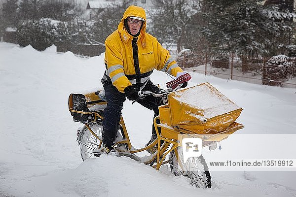 Mann  Briefträger  Briefträger auf gelbem Postfahrrad bei winterlichen Bedingungen  Bayern  Deutschland  Europa