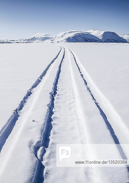 Fahrspuren führen über einen gefrorenen Fjord auf ferne Berge zu  Baffin Island  Nunavut  Kanada  Nordamerika
