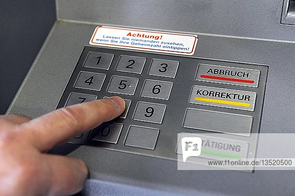 Person  die die PIN an einem Geldautomaten eingibt