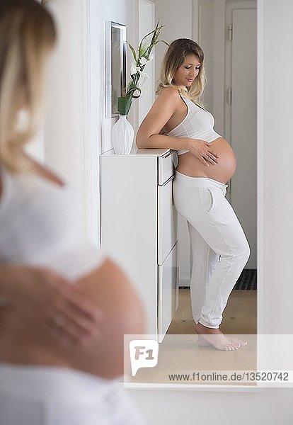 Woman in her ninth month pregnant  looks at herself in the mirror  Germany  Europe