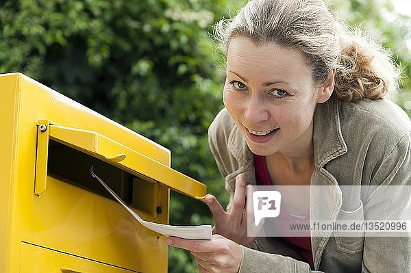 Junge Frau wirft einen Brief in einen Briefkasten