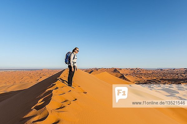 Woman stands on a red sand dunes in the desert  dune landscape Erg Chebbi  Merzouga  Sahara  Morocco  Africa