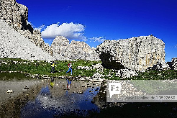 Wanderer unterhalb des Paternsattels spiegeln sich in einer Pfütze  Weg 101  hinter dem Gipfel des Einser  Sextner Dolomiten  Hochpustertal  Südtirol  Italien  Europa