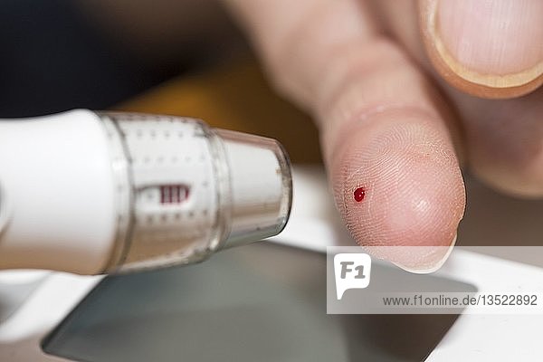 Diabetics taking a blood glucose test  with a lancing device a drop of blood is produced at the fingertip  Germany  Europe