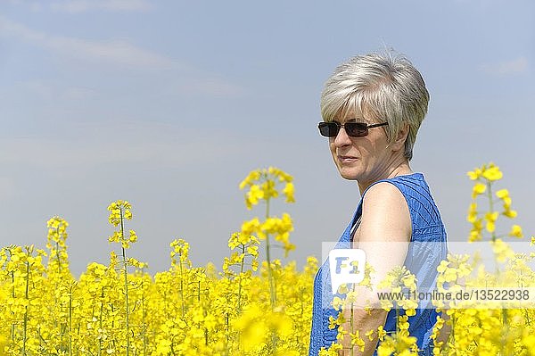 Frau steht in einem gelben Rapsfeld