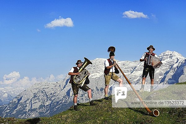 Three folk musicians play in front of mountain panorama  Bergfexn trio in traditional costume on the Eggenalm  behind Loferer Steinberge  Reit im Winkl  Bavaria  Upper Bavaria  Germany  Europe