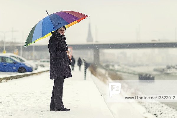 Frau steht mit buntem Regenschirm im Winter am Ufer des Rheins Düsseldorf Rheinland Nordrhein-Westfalen Deutschland Europa