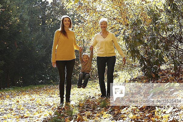 Three generations of women. Grandmother  daughter  granddaughter walking in autumnal forest  Czech Republic  Europe