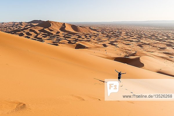 Frau läuft bergab  rote Sanddünen in der Wüste  Dünenlandschaft Erg Chebbi  Merzouga  Sahara  Marokko  Afrika