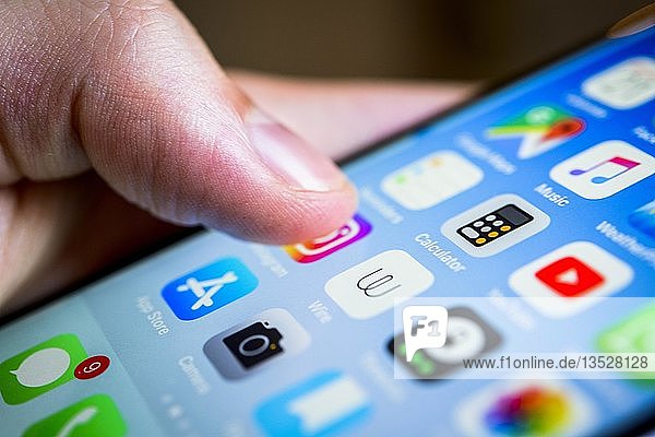 Finger berührt Display  Touchscreen eines iPhone  Smartphone  Homescreen  viele App-Symbole auf dem Display  Apps  iOS  Detail  Nahaufnahme  Deutschland  Europa