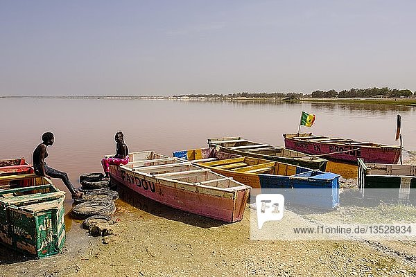 Zwei junge Frauen sitzen auf bunten Holzbooten am Lac Rose  Region Dakar  Senegal  Afrika
