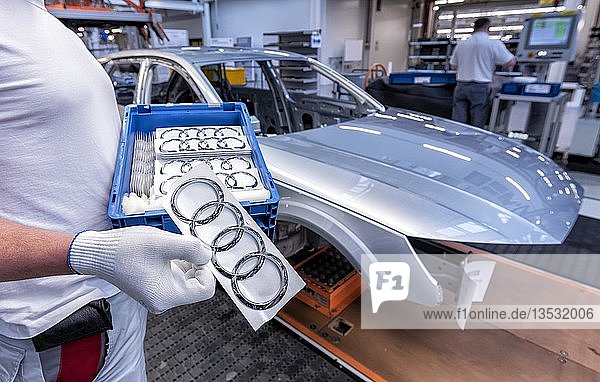 Ein Audi-Mitarbeiter hält einen Kasten mit Audi-Logos in Händen auf der Montagelinie Audi A4 im Werk der Audi AG in Ingolstadt  Bayern  Deutschland  Europa