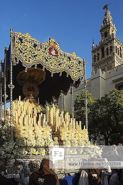 Büßer und dekorierter Wagen mit der gesegneten Jungfrau bei der Semana Santa Prozession Karwoche an der maurischen Giralda Sevilla Andalusien Spanien Europa