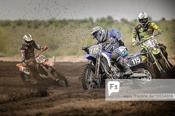 Three motocross riders on a track during a race  Grevenbroich  North Rhine-Westphalia  Germany  Europe