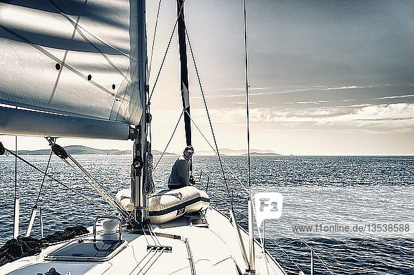 Skipper sitting at the bow of his sailing yacht looking towards aft  Adriatic Sea  Croatia  Europe