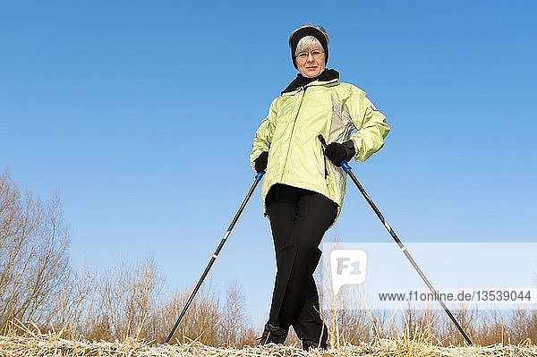 Frau  50+  beim Nordic Walking an einem sonnigen Wintertag