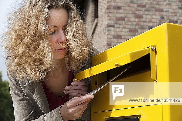 Junge Frau wirft einen Brief in einen Briefkasten