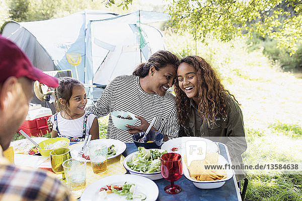 Liebevolle  glückliche Familie beim Mittagessen am Campingtisch