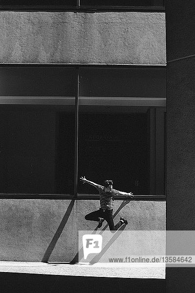 Exuberant young man jumping against urban wall