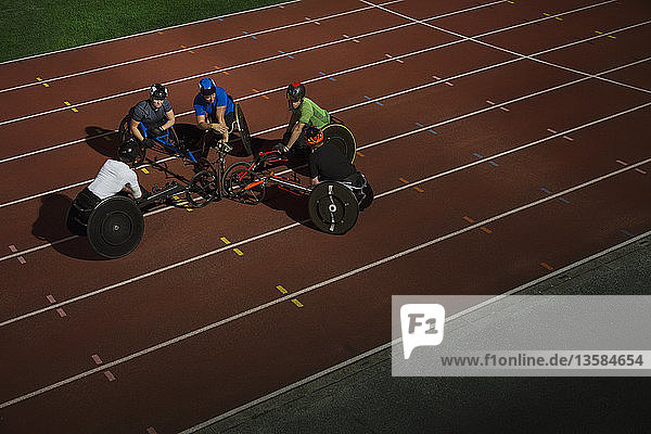 Querschnittsgelähmte Athleten kauern auf einer Sportbahn und trainieren für ein Rollstuhlrennen