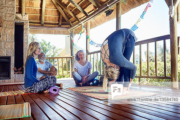 Yogalehrerin demonstriert die Vorwärtsfalte in einer Hütte während eines Yoga-Retreats