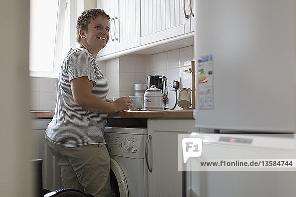 Smiling young woman preparing tea in apartment kitchen