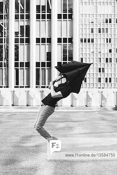 Mann tanzt mit Regenschirm über dem Kopf