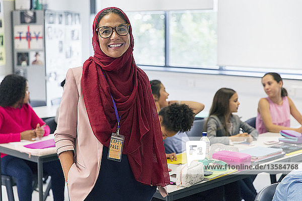 Porträt einer lächelnden  selbstbewussten Lehrerin mit Hidschab im Klassenzimmer