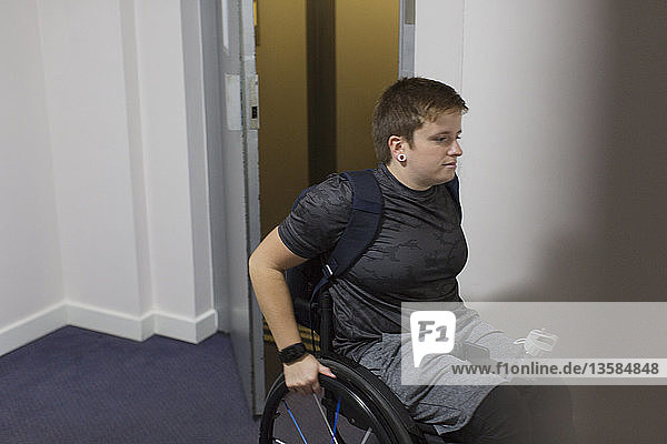 Young woman in wheelchair getting out of elevator