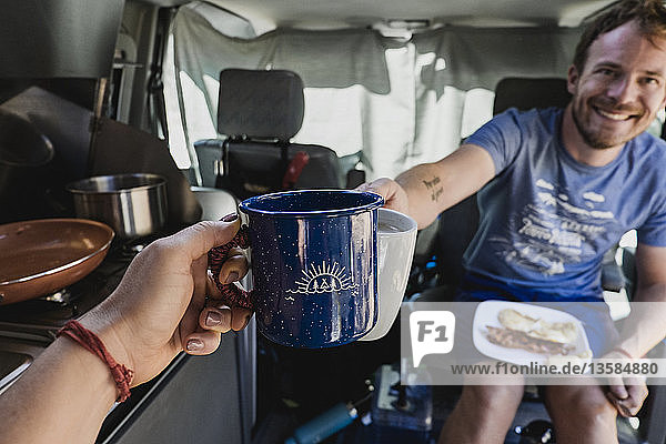 Persönliche Perspektive Paar toastet Kaffeetassen im Wohnmobil