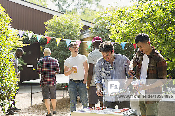 Male friends enjoying barbecue in sunny backyard