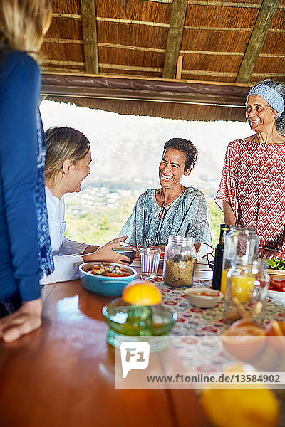 Glückliche Freunde genießen ein gesundes Frühstück in einer Hütte während eines Yoga-Retreats