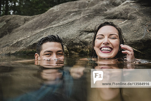 Porträt verspieltes junges Paar beim Schwimmen im See