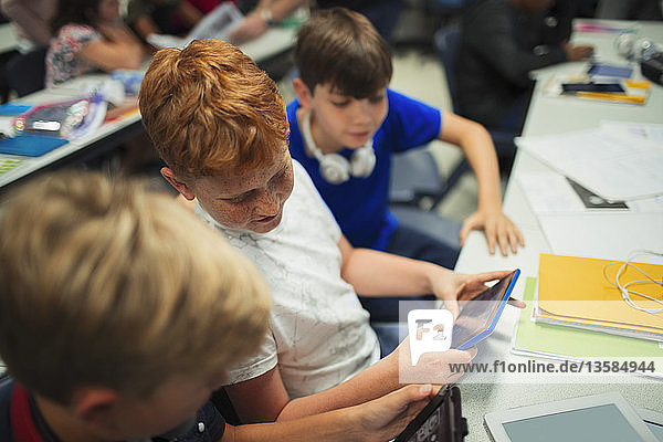 Junge Schüler der Junior High School benutzen digitale Tablets am Schreibtisch im Klassenzimmer