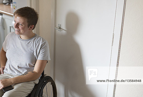 Lächelnde junge Frau im Rollstuhl zu Hause