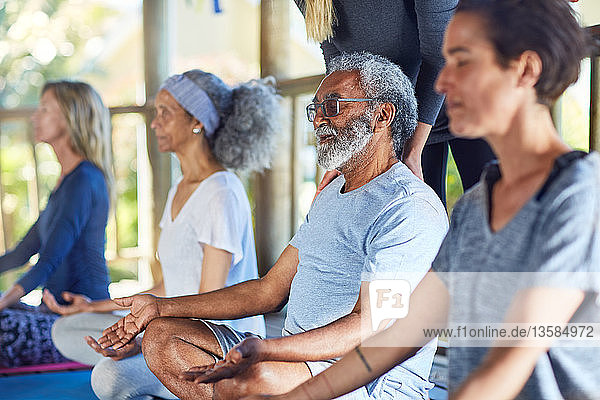 Gelassener älterer Mann meditiert während eines Yoga-Retreats